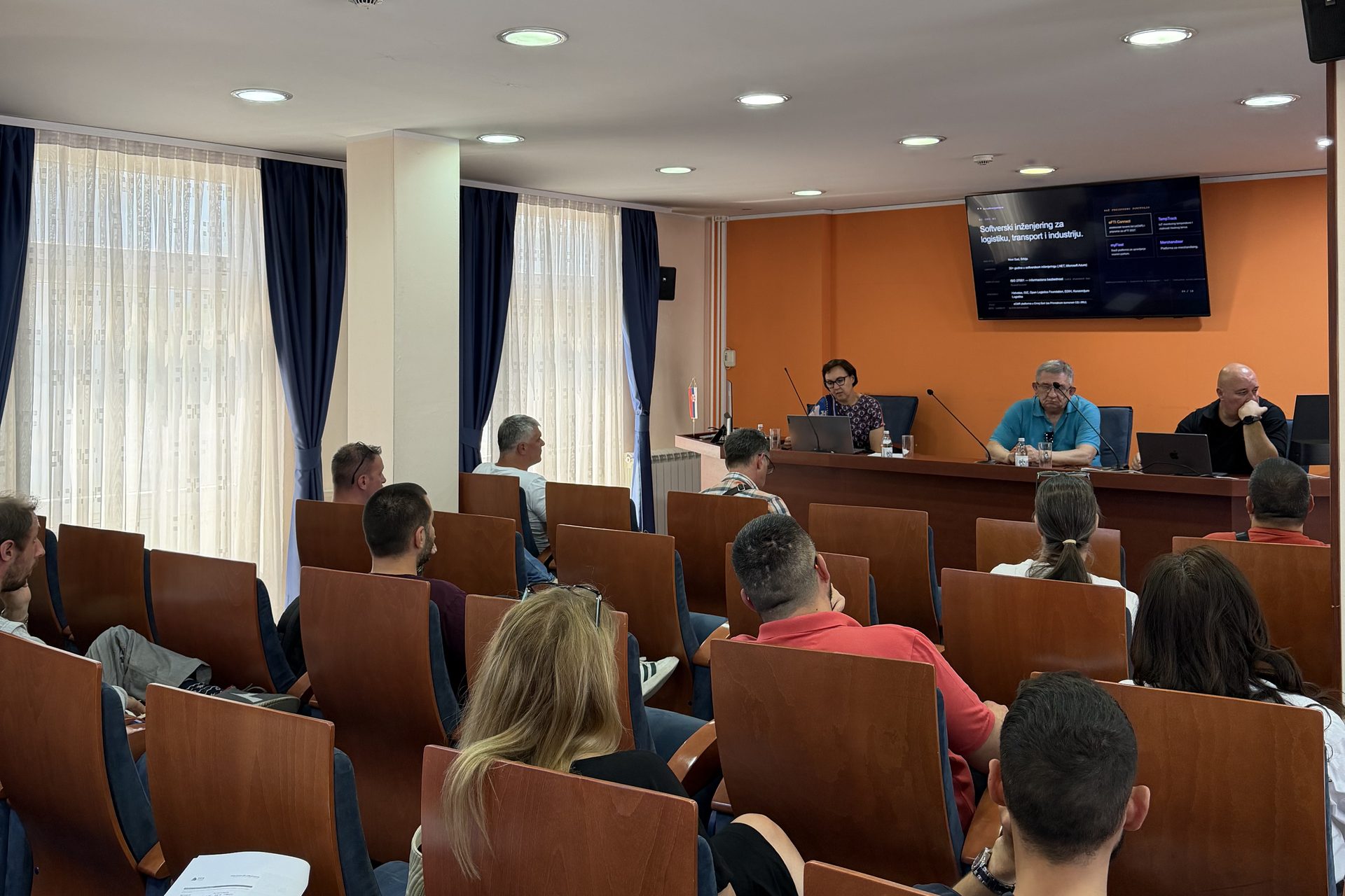 Carriers and forwarders seated in the hall of the Regional Chamber of Commerce in Novi Sad, facing a panel table and a screen showing an eFTI Connect slide