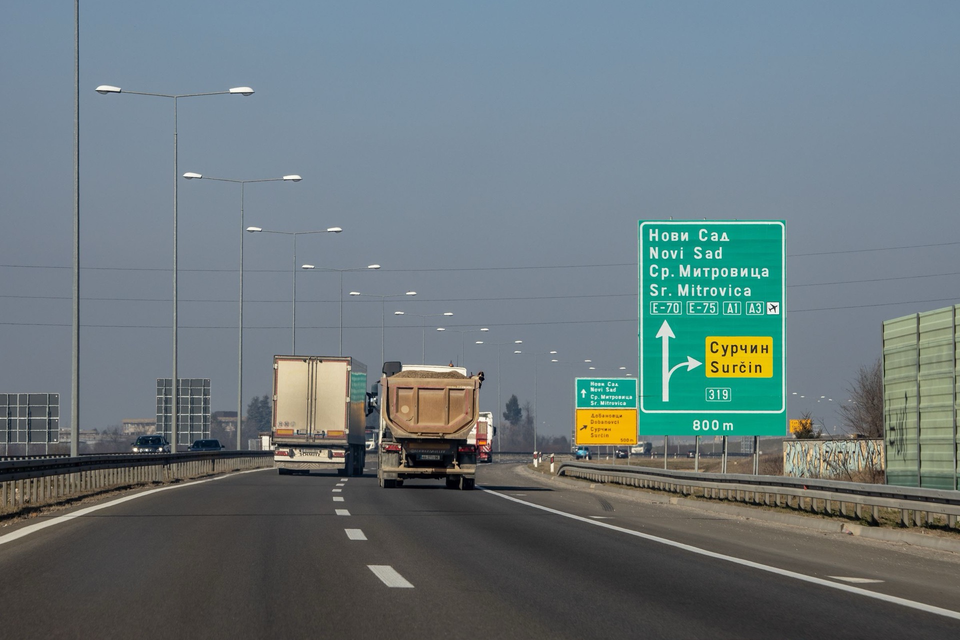 Kamioni na autoputu E-70/E-75 kod Beograda, ispod dvojezične table za Novi Sad i Sremsku Mitrovicu
